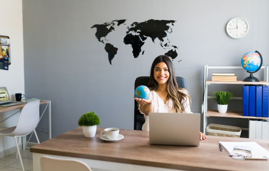 Responsable séjours scolaires assise à son bureau avec une mappe-monde dans la main