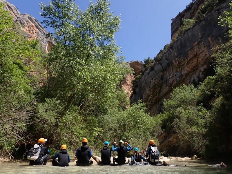 groupe d\élèves assis dans un canyon avec leur combinaison et leur casque